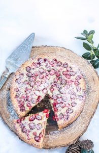 cranberry olive oil cake on a wood cake stand in the snow - holiday baking