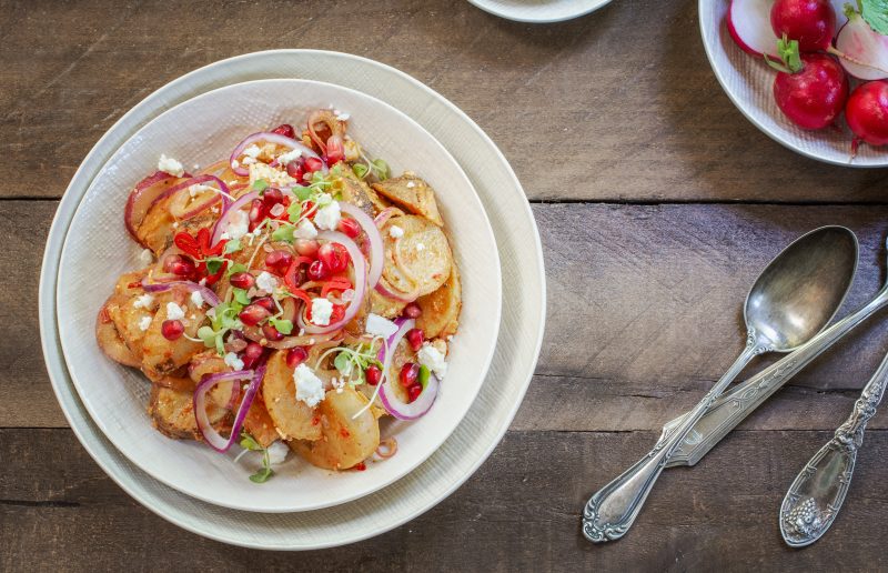 Overhead of white bowl with potato salad on wood table