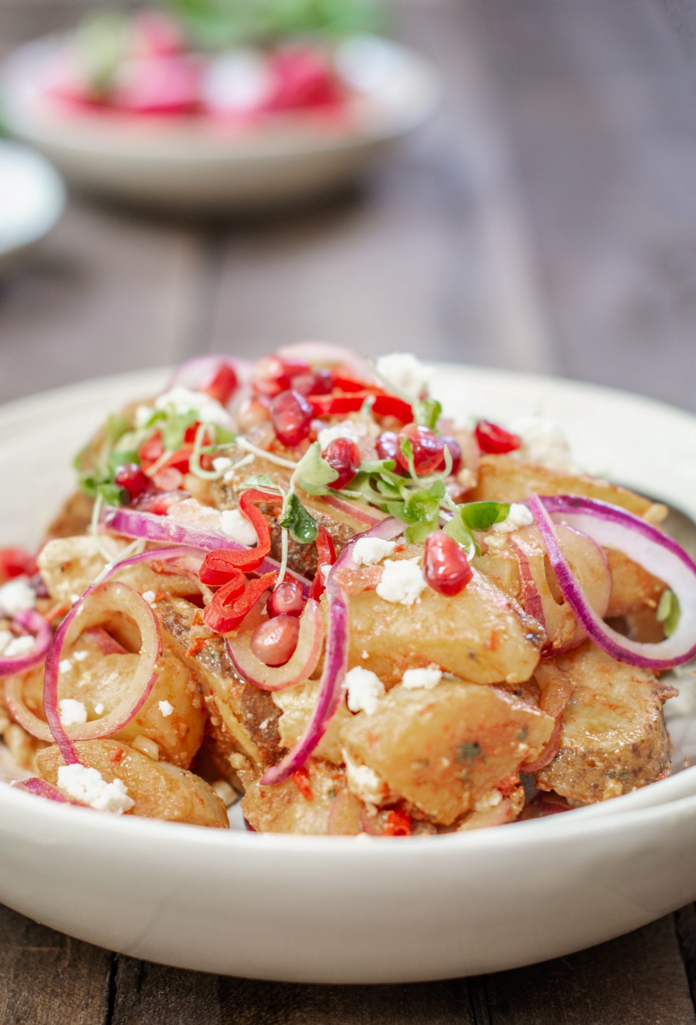 Bowl filled with Moroccan Potato Salad, pomegranate seeds and onions