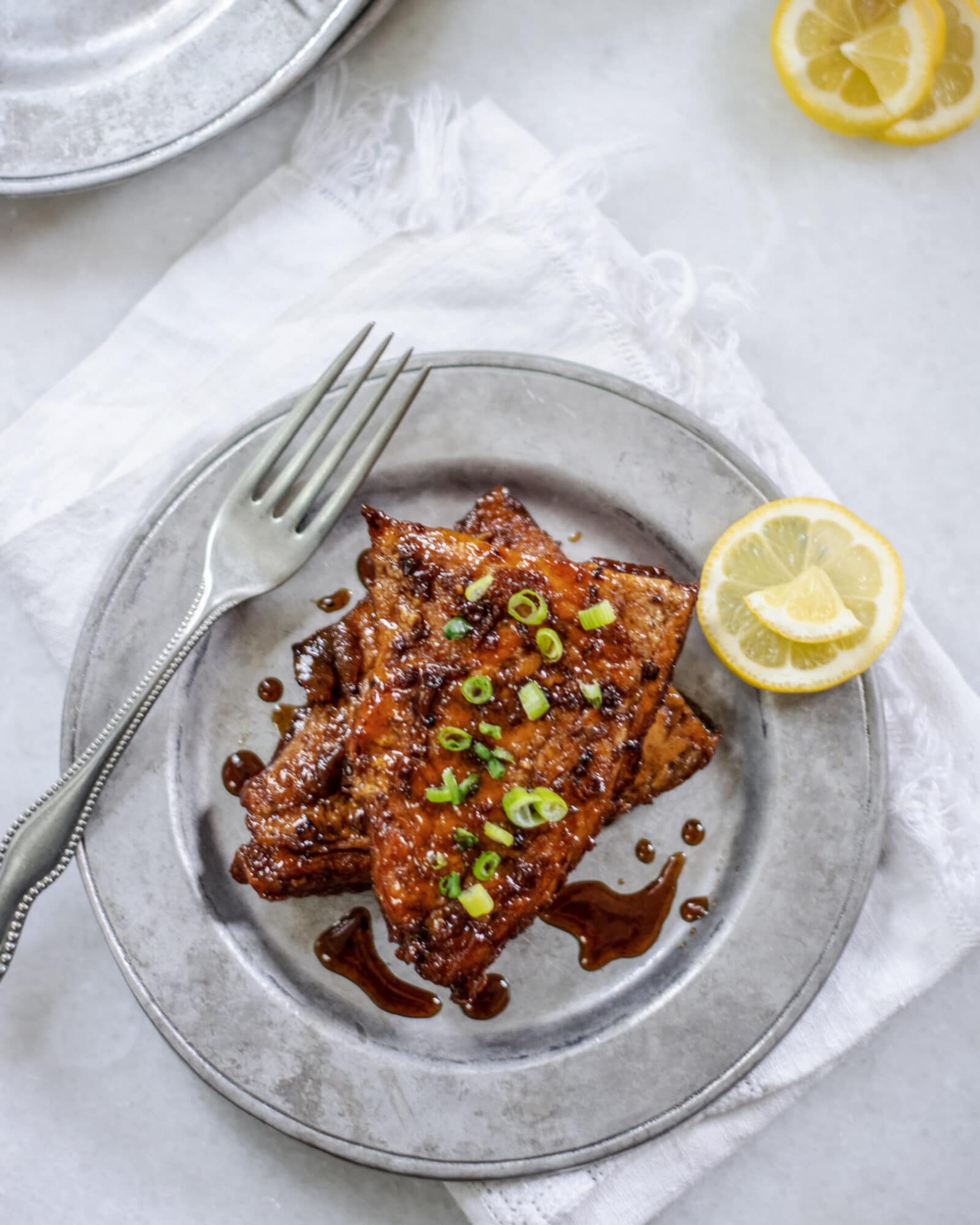 White table with silver plate and balsamic glazed salmon and lemons