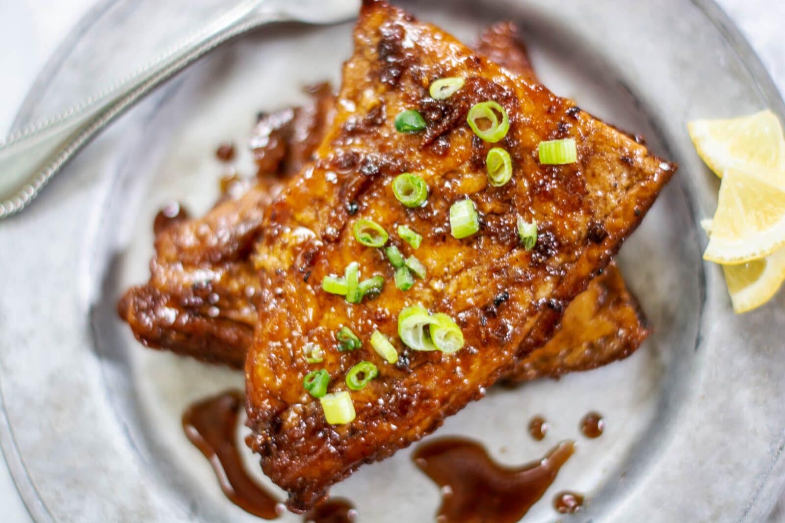 Silver-plate-with-glazed-salmon,-spring-onions-and-lemons