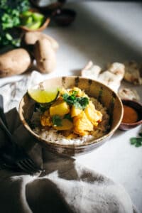 Bowl of rice with butternut potato curry on white surface